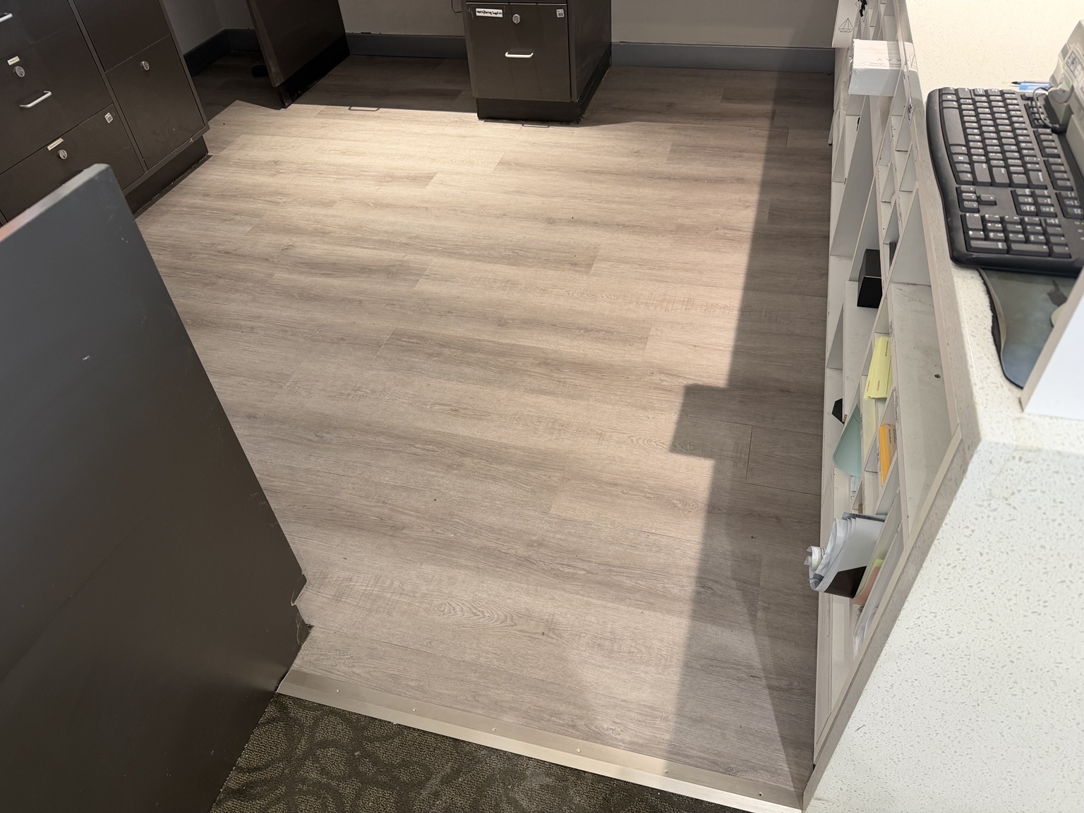 Completed wood-look flooring at KAY Jewelers with a metal transition to the adjacent carpet